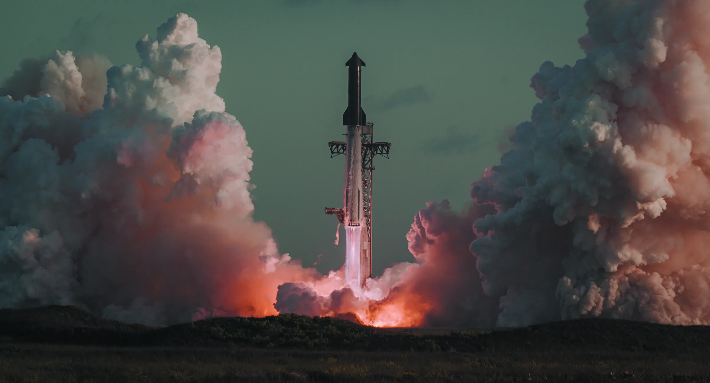 SpaceX Starship and Super Heavy lifting off from Starbase, flames and towering clouds of exhaust on both sides at dusk