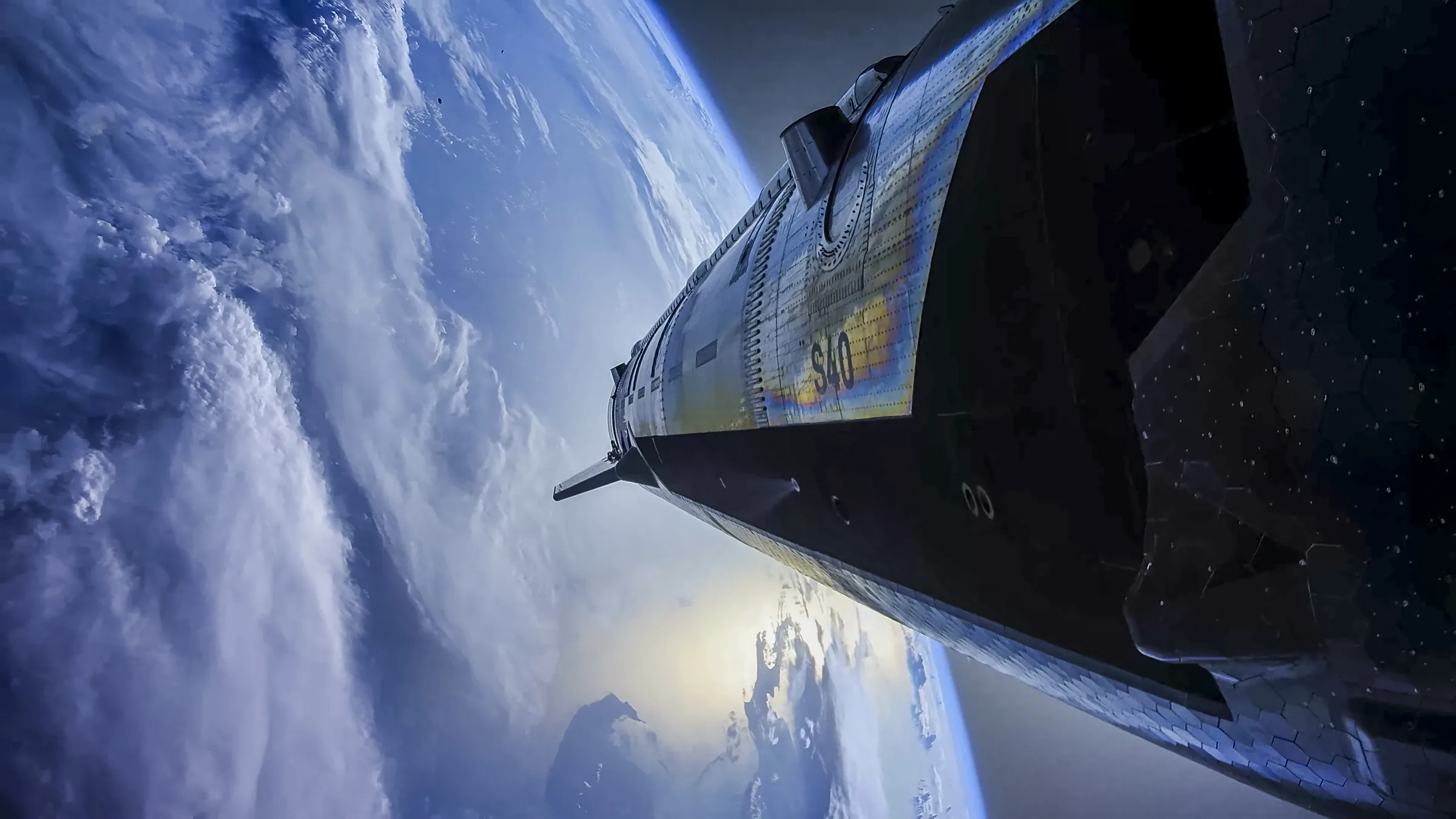 SpaceX Starship seen from an onboard camera in space, its steel hull glinting above Earth's clouds and blue horizon