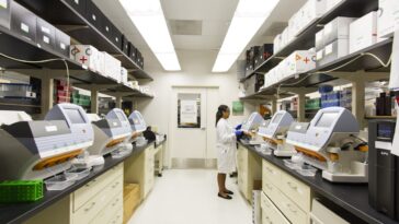 Scientist operating genomic sequencing machines in a biotech lab